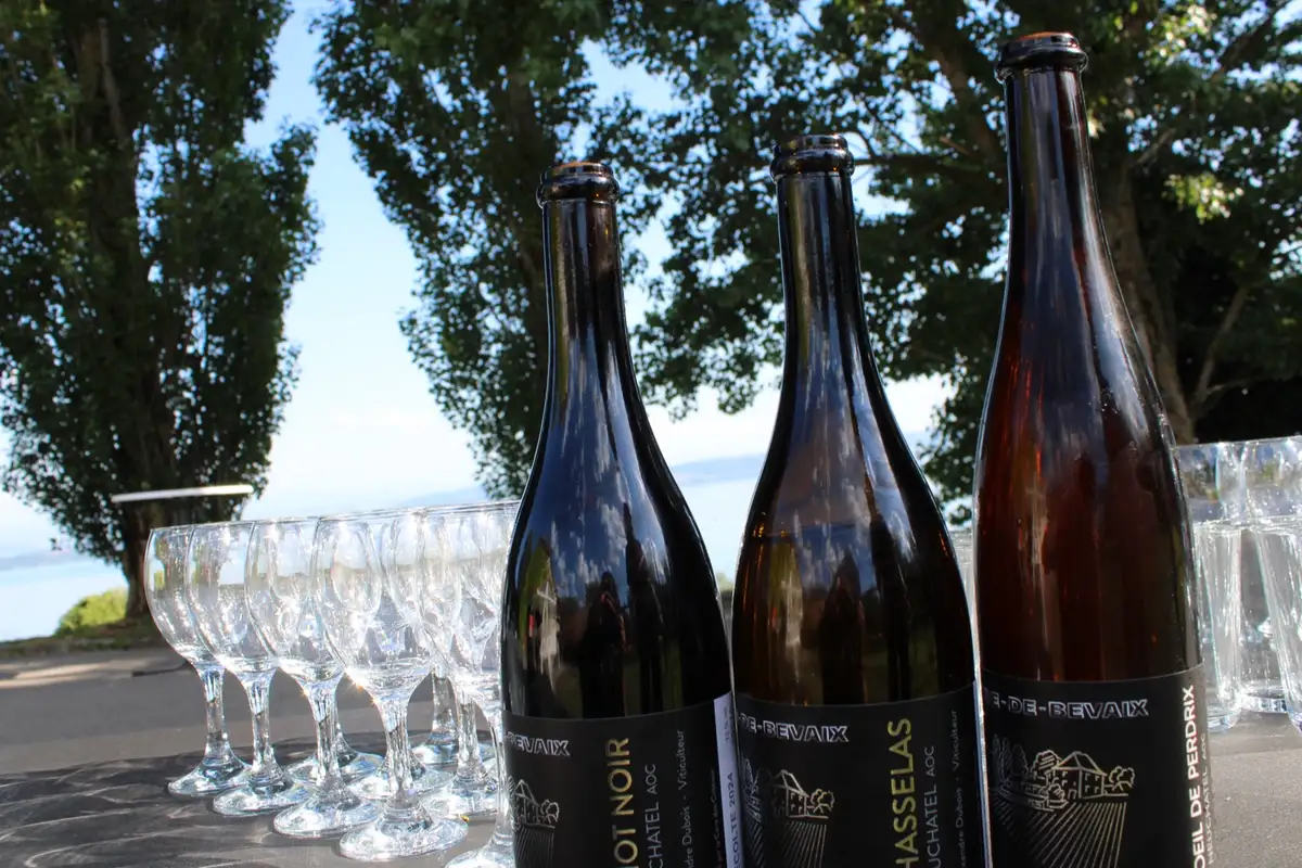 Bouteilles de vin de Neuchâtel et verres dressés face au lac